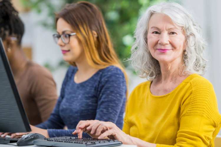 Auf diesem Bild sind zwei Frauen zu sehen, die vor einem Computer sitzen. 