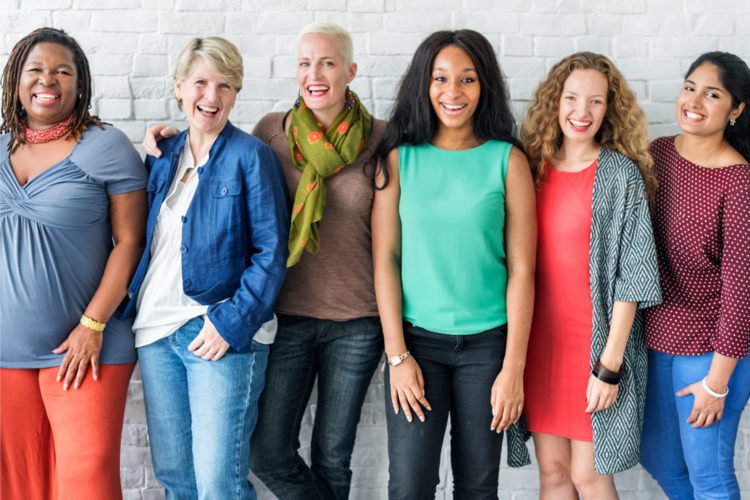 Auf diesem Bild sind sechs Frauen zu sehen, die in einer Reihe stehen und in die Kamera lachen.