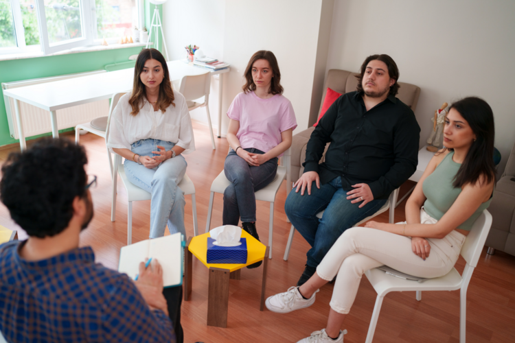 Das Bild zeigt eine Gruppe von Personen in einem Stuhlkreis.