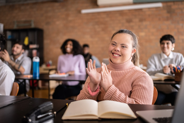 Auf diesem Bild ist eine Person mit Beeinträchtigung zu sehen, die in einem Klassenraum sitzt.