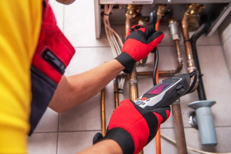 Auf diesem Bild arbeitet ein Handwerker an Heizungsrohren.