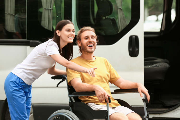 Auf dem Bild ist eine Person im Rollstuhl mit einer Begleitung zu sehen. 