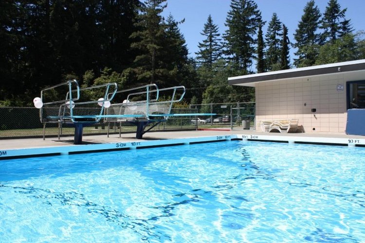 Auf diesem Bild ist ein Schwimmbecken im Außenbereich mit zwei Sprungtürmen zu sehen. 