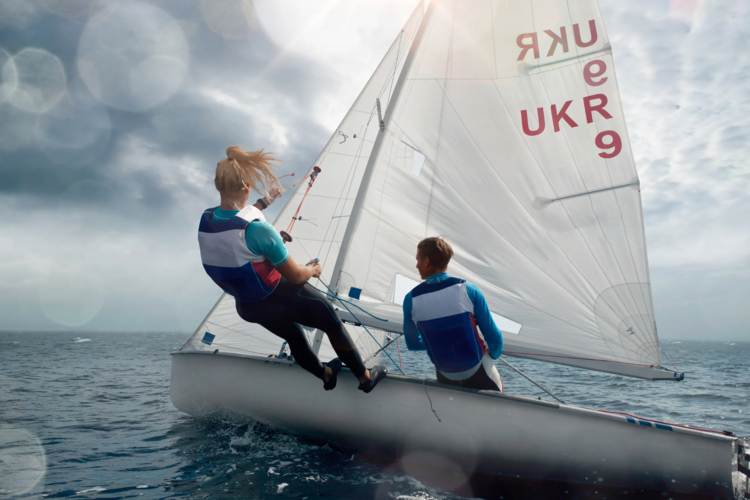 Auf diesem Bild ist ein Segelboot auf dem Wasser mit Besatzung zu sehen. 